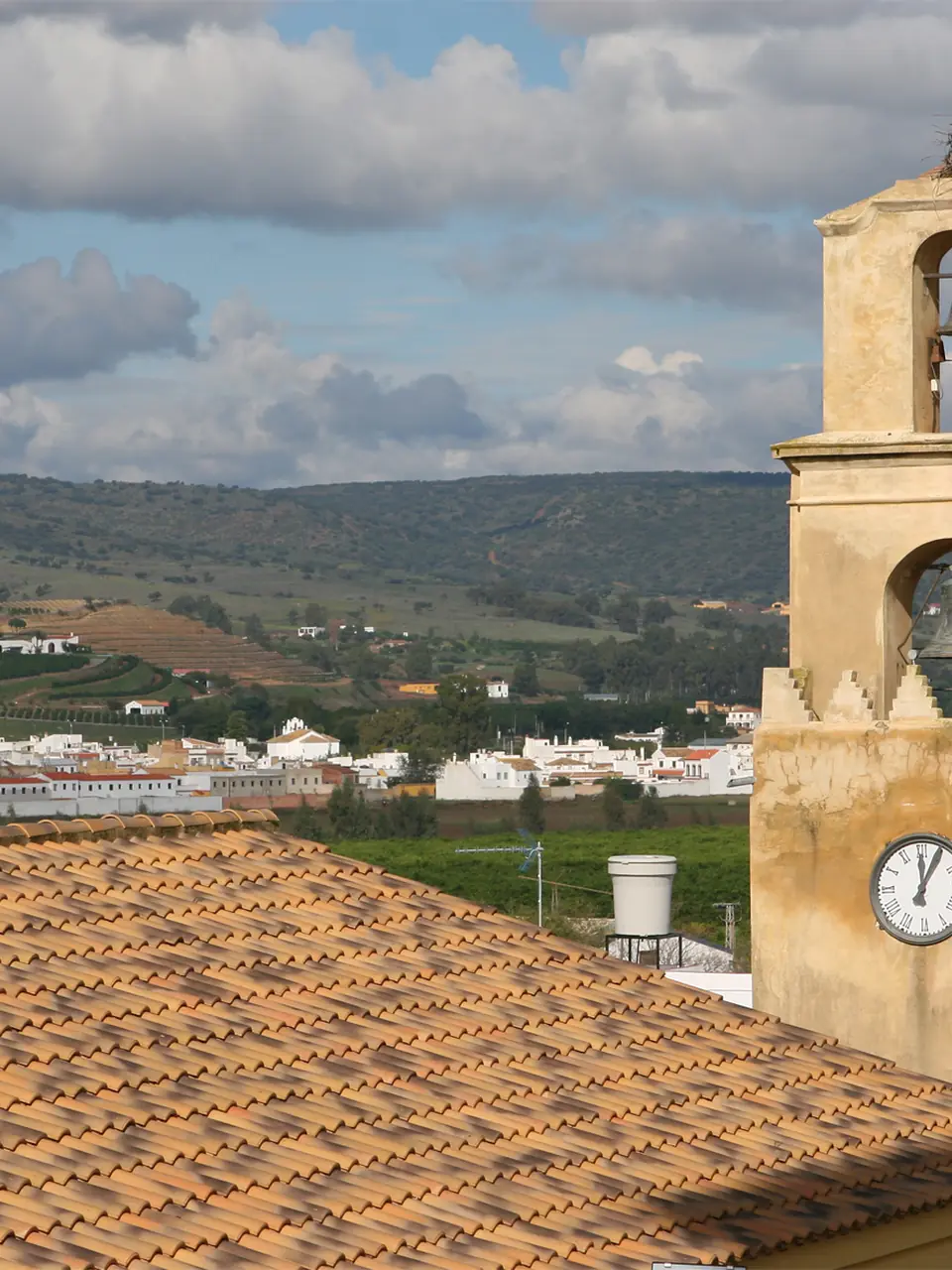 Torre del reloj de Cantillana, con nido de cigüeña, y la vega del Guadalquivir al fondo