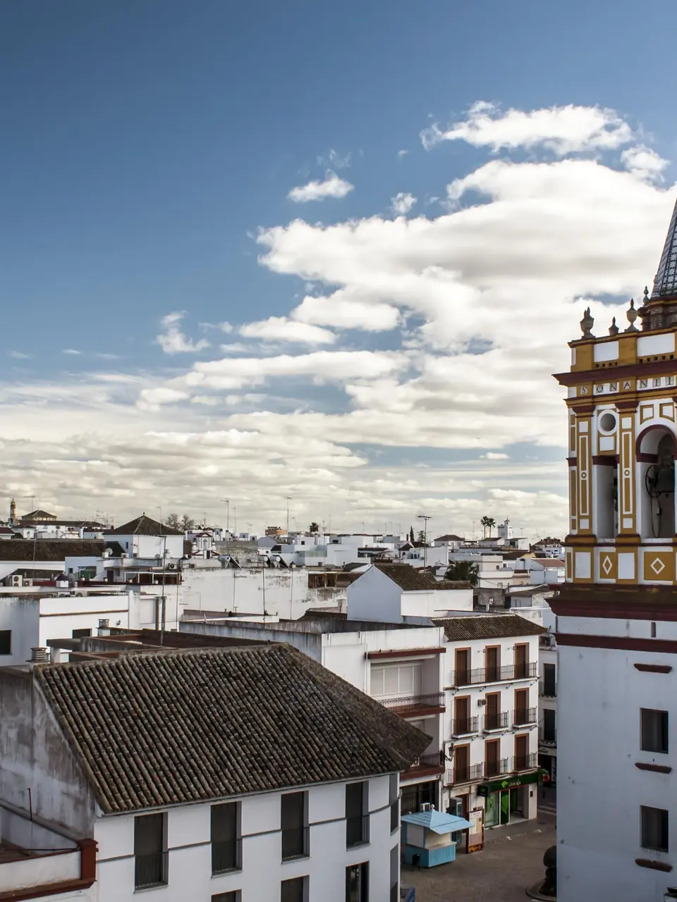 Torre de una iglesia sobre los tejados de Sanlúcar la Mayor